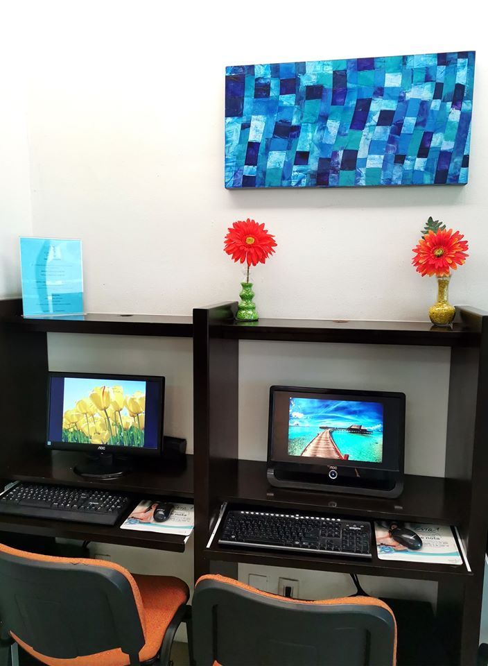 Dos monitores de computadora en un escritorio con una pintura encima de ellos