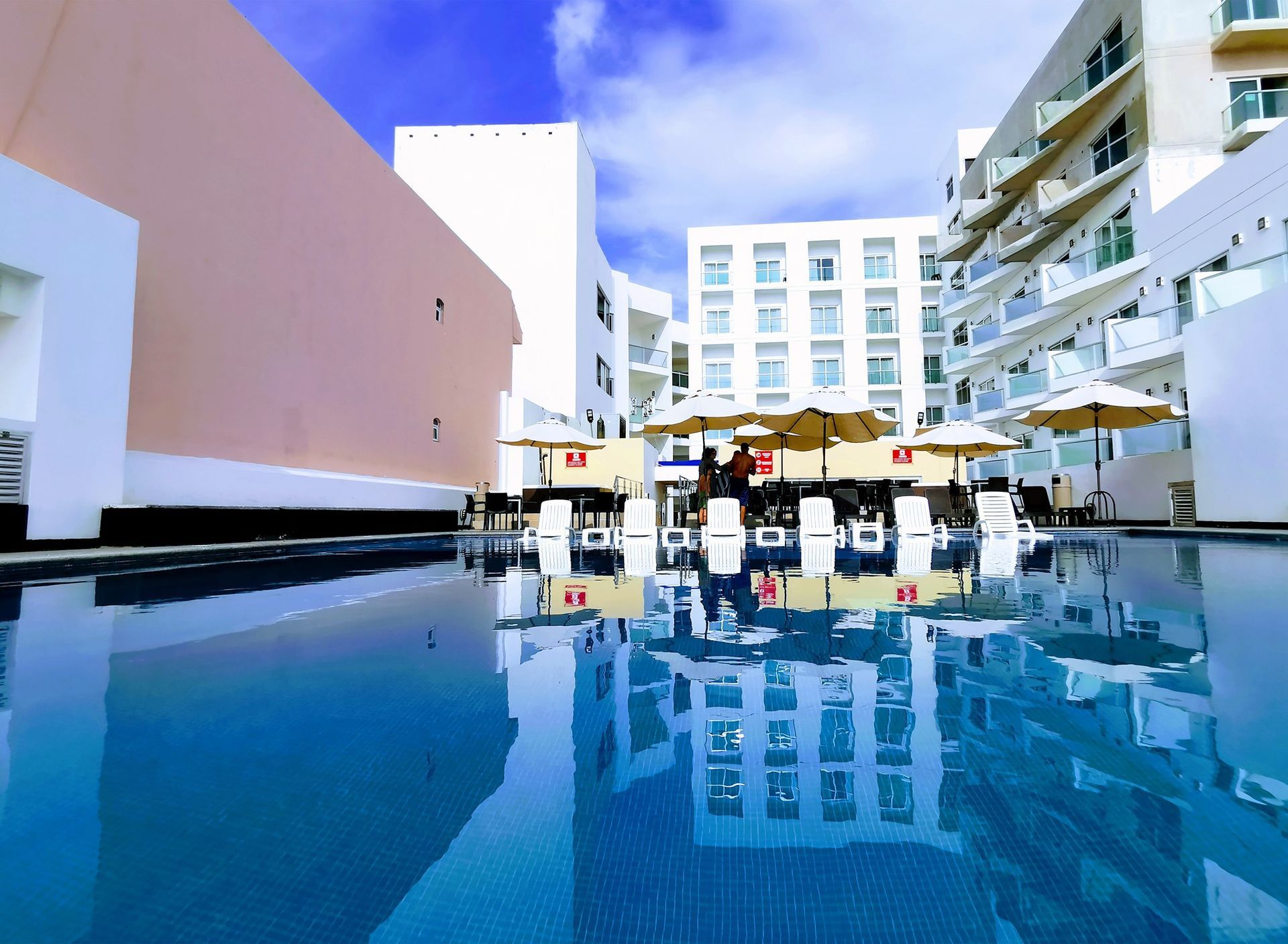 Una gran piscina rodeada de edificios y sombrillas.