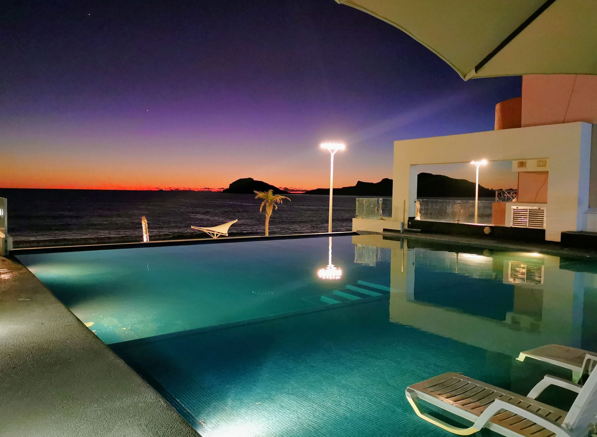 A large swimming pool with a view of the ocean at night