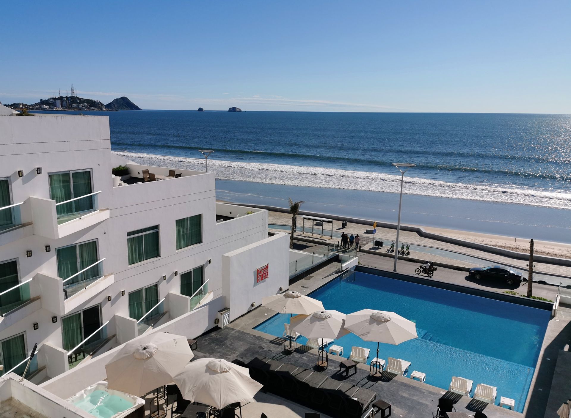 An aerial view of a hotel with a swimming pool and umbrellas
