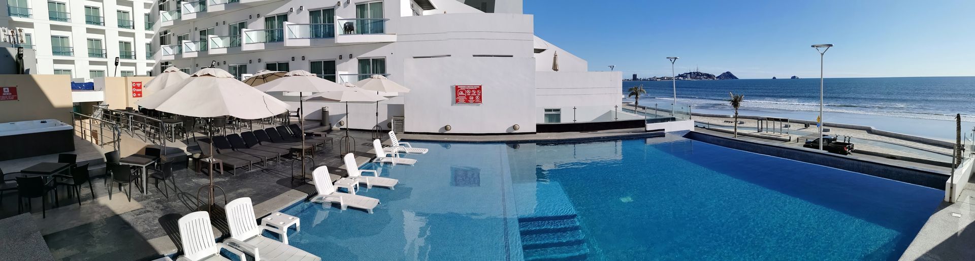 Gran piscina frente a la playa está rodeada de sillas en Hotel Coral Island