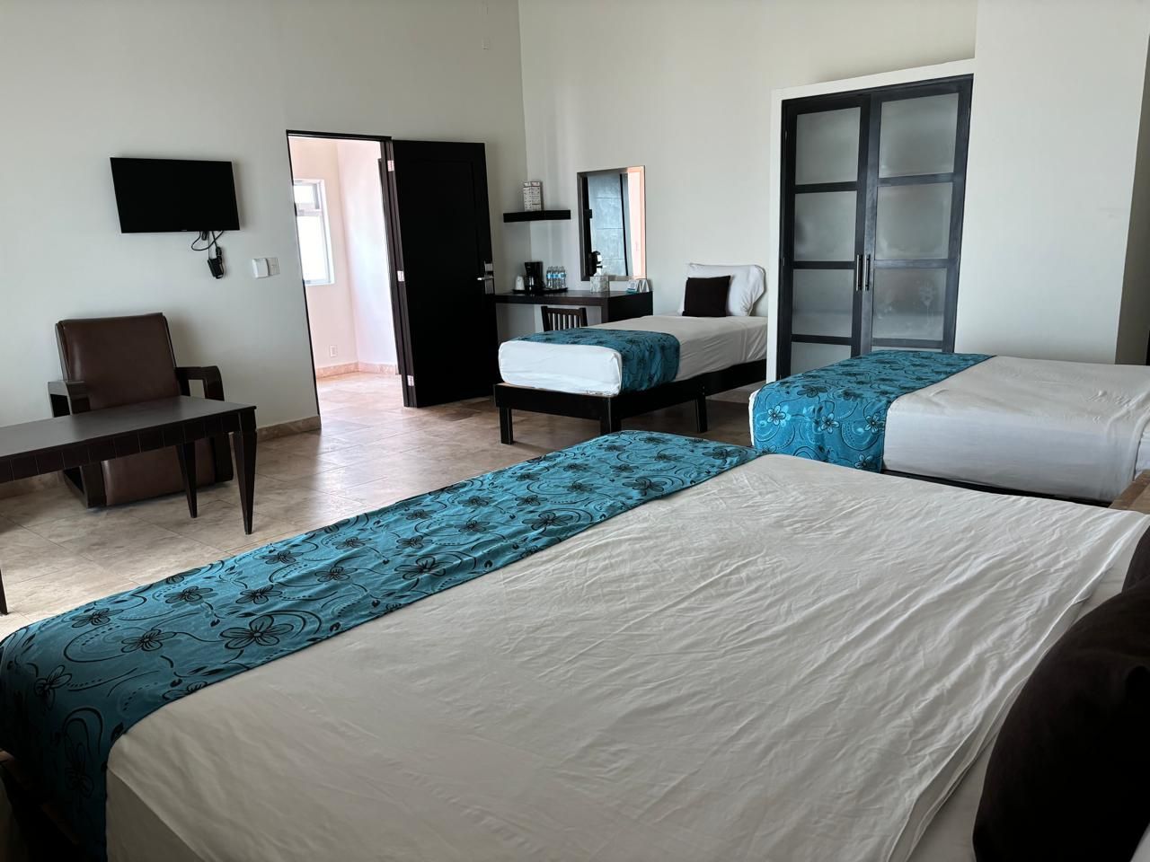 Una habitación de hotel en Mazatlan con dos camas y una silla