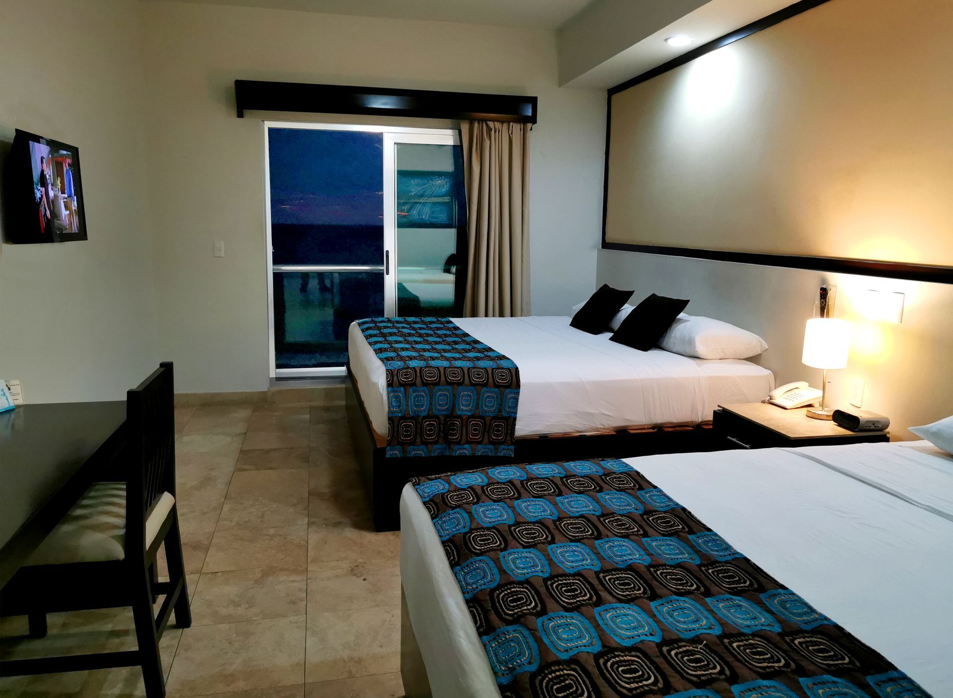 A hotel room with two beds , a desk and a television.