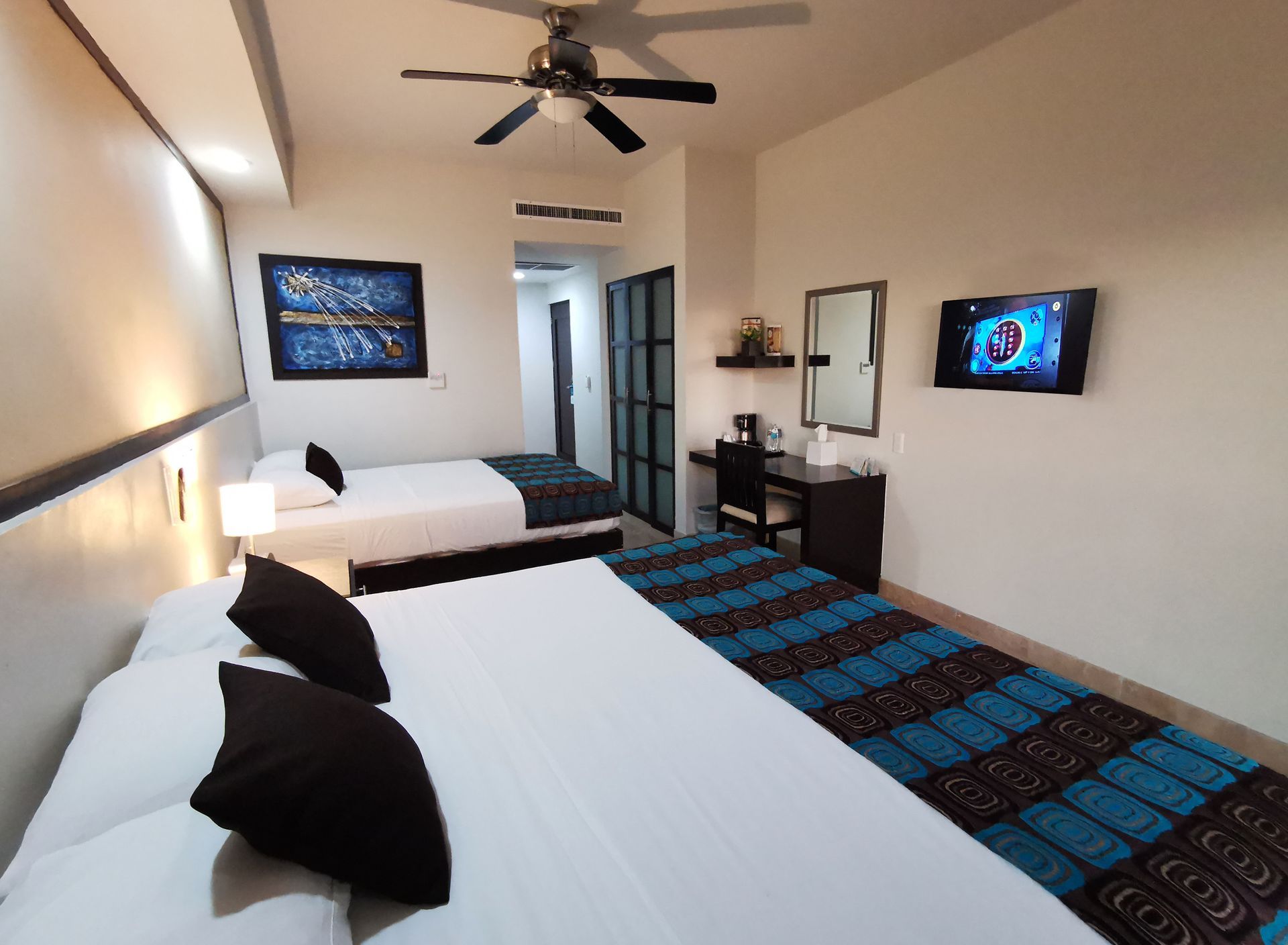 A hotel room with two beds and a ceiling fan