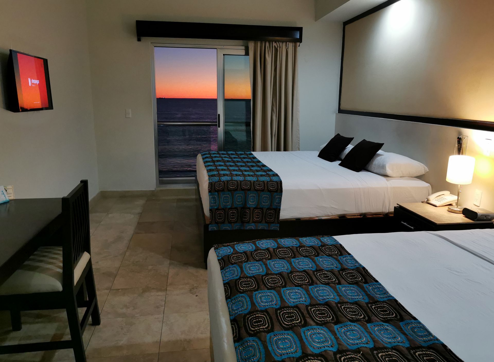 A hotel room with two beds , a desk and a television.