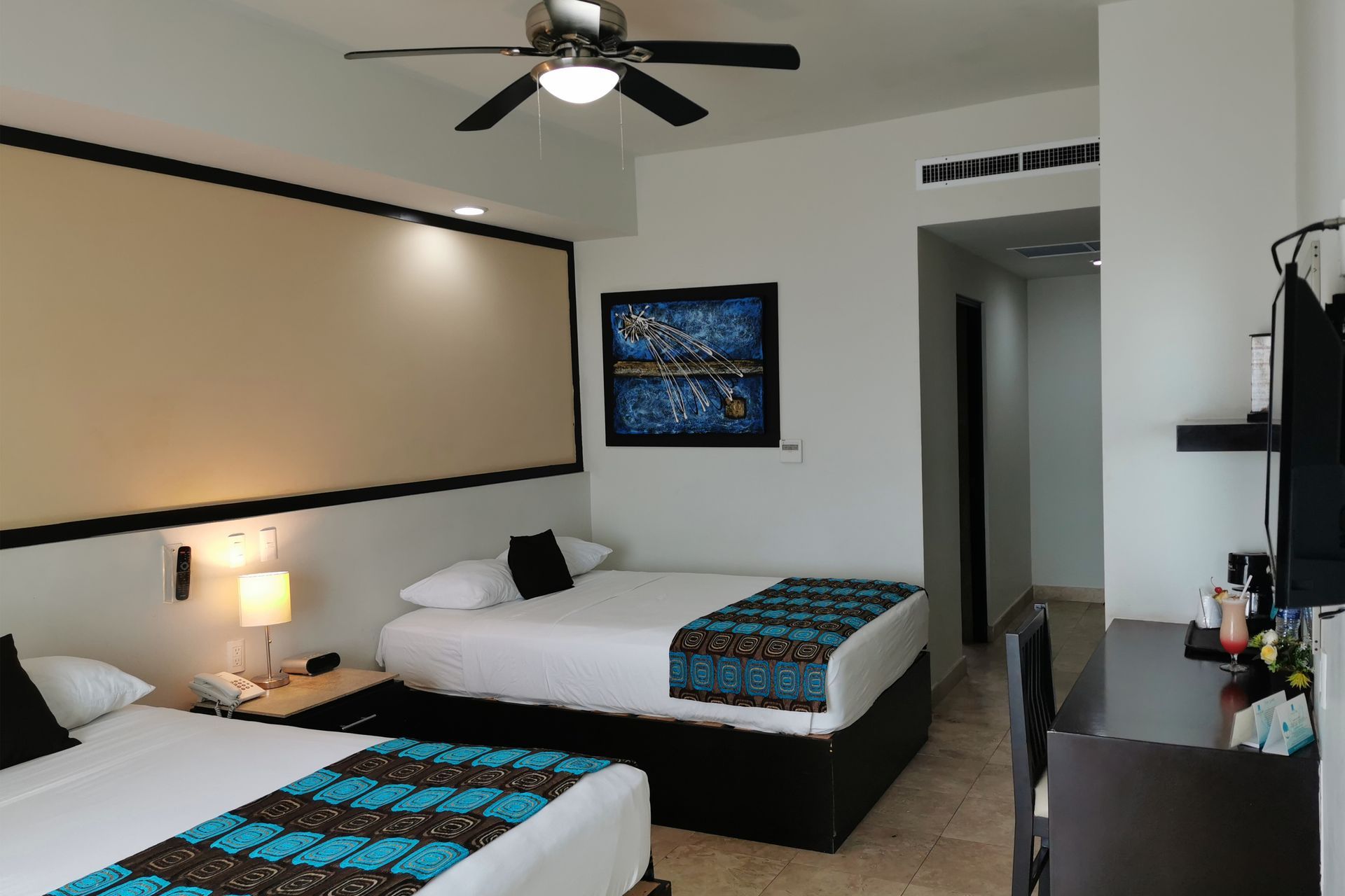 A hotel room with two beds and a ceiling fan.