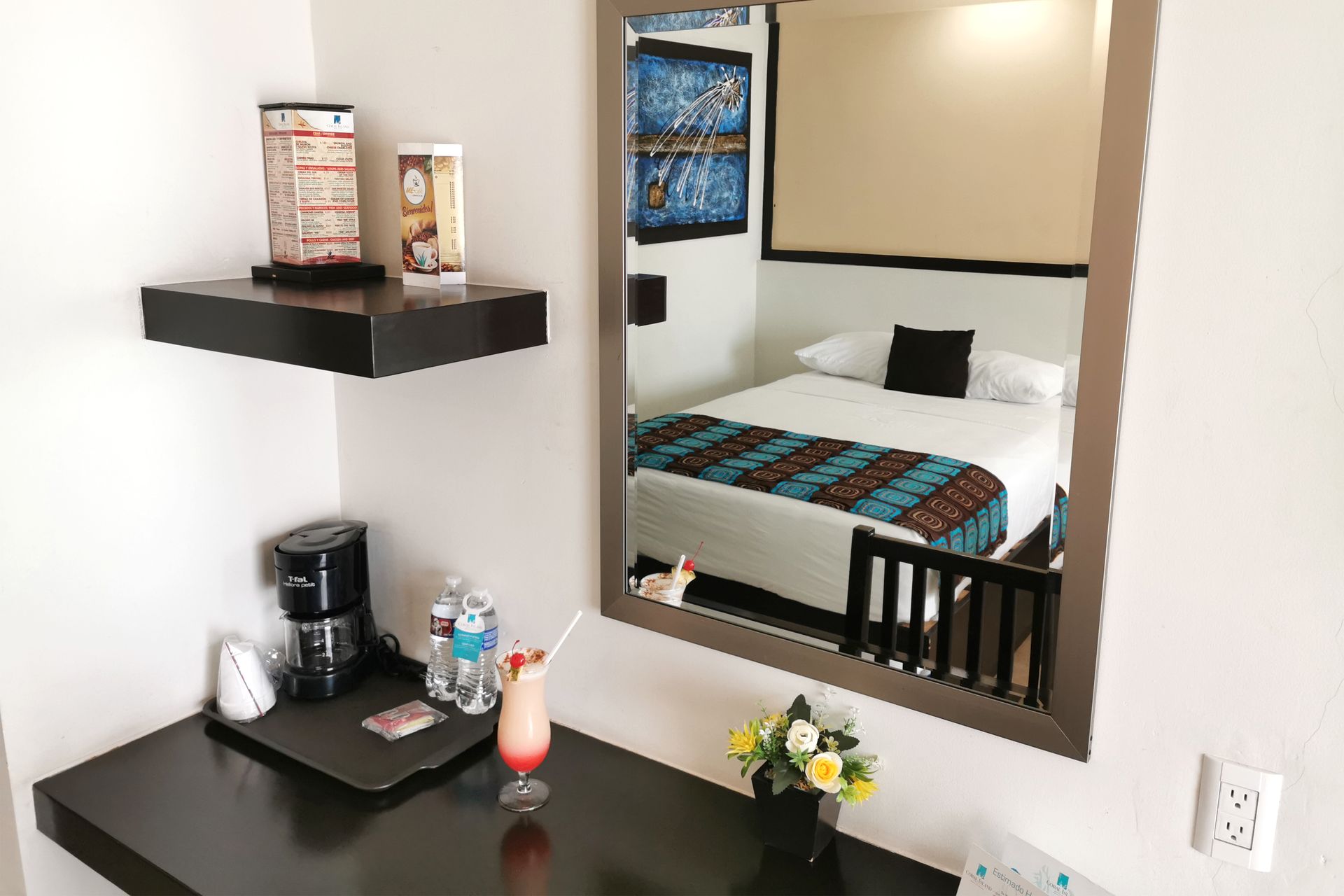A hotel room with a bed and a desk with a drink on it.