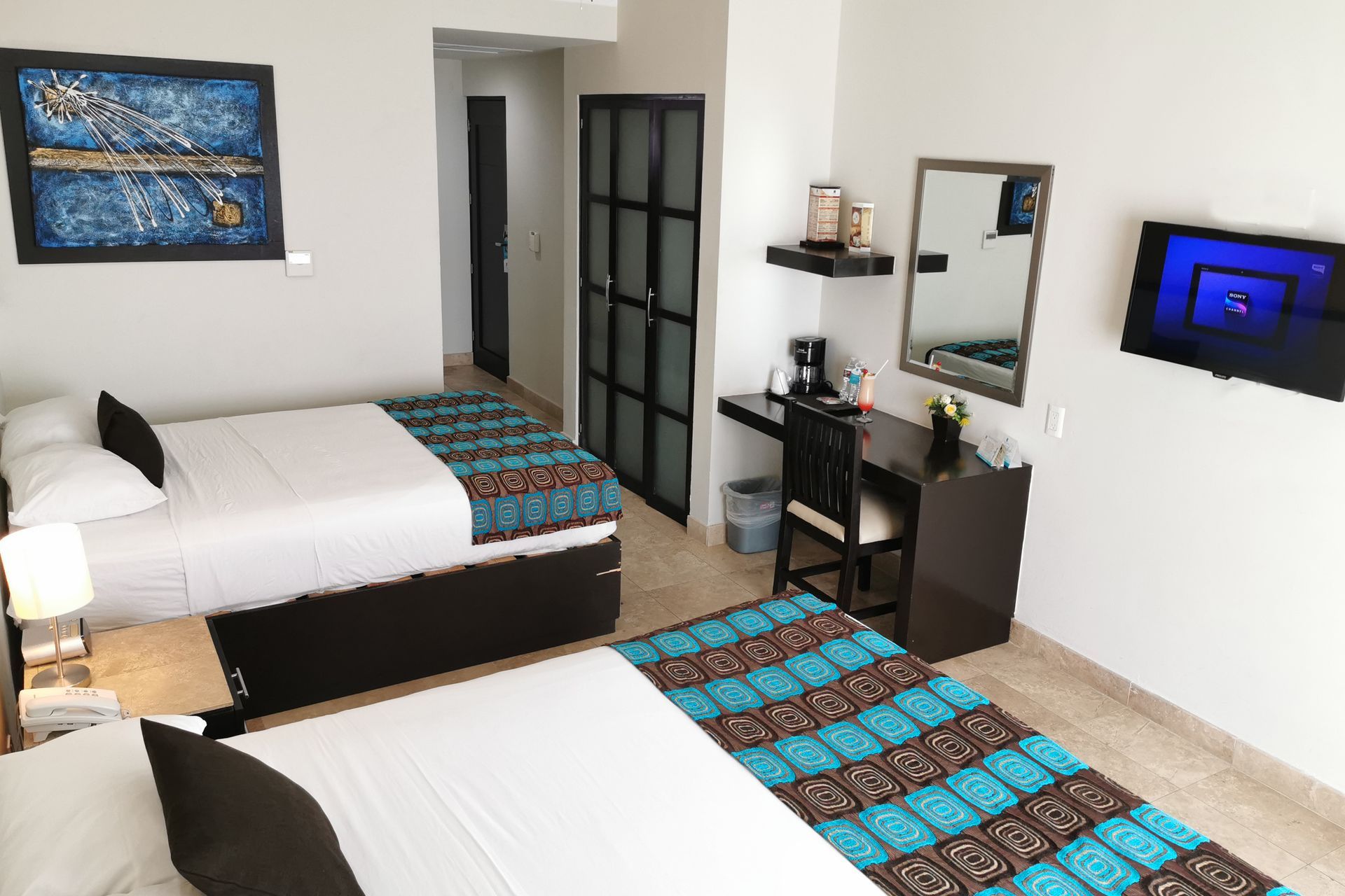 A hotel room with two beds , a desk , a television and a mirror.