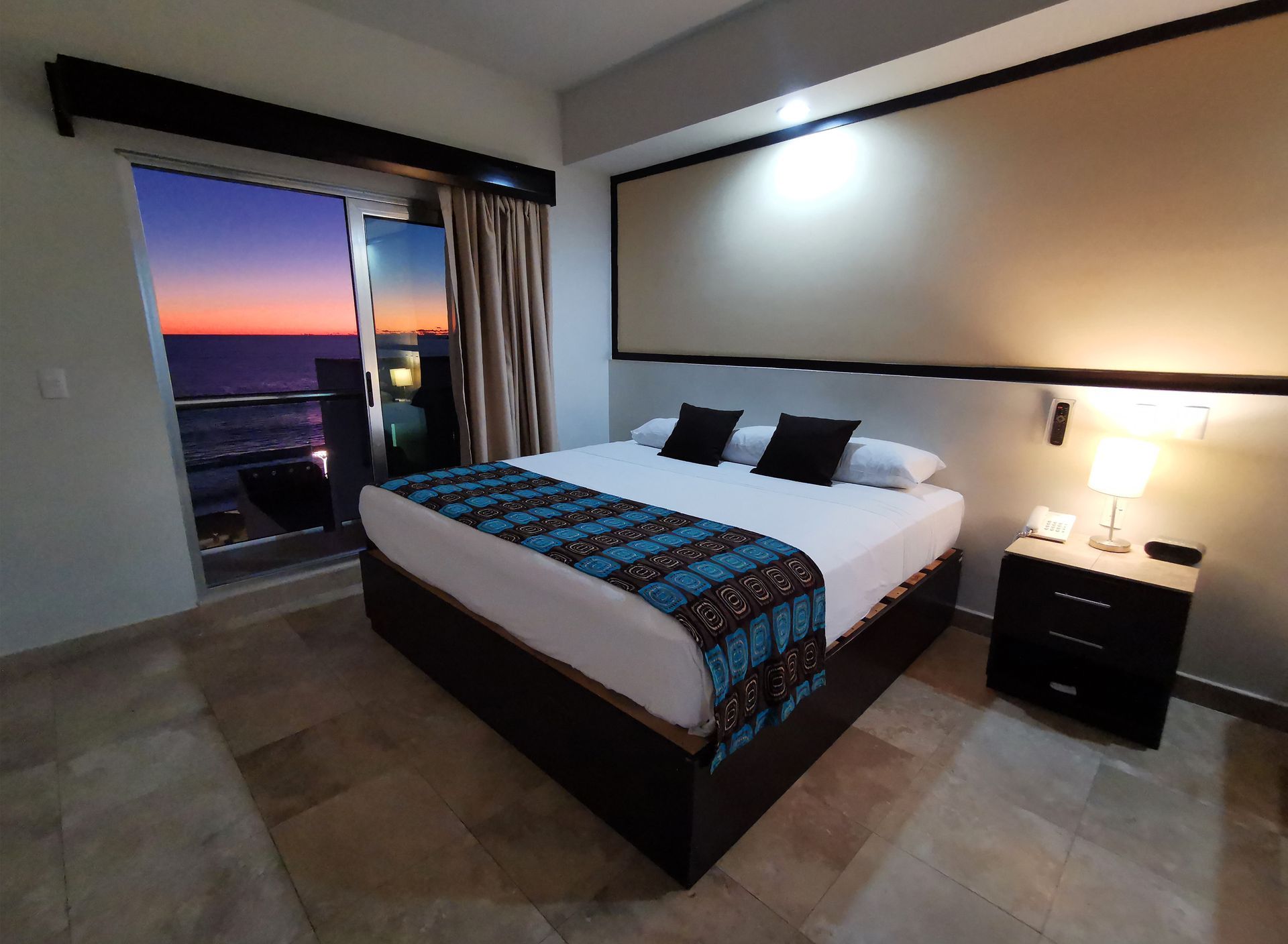 A hotel room with a large bed and a balcony overlooking the ocean