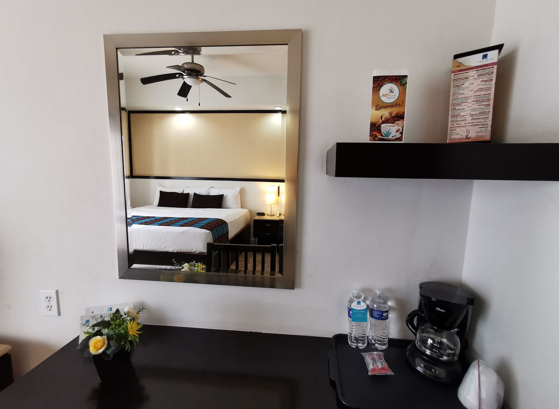 A hotel room with a reflection of a bed in the mirror
