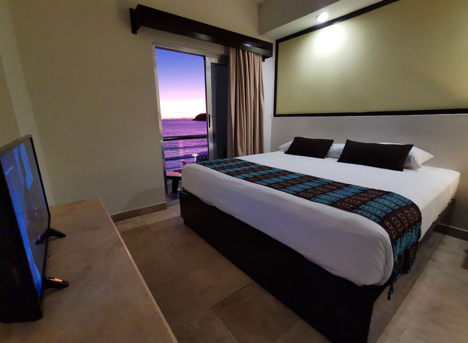 A hotel room with a large bed and a flat screen tv
