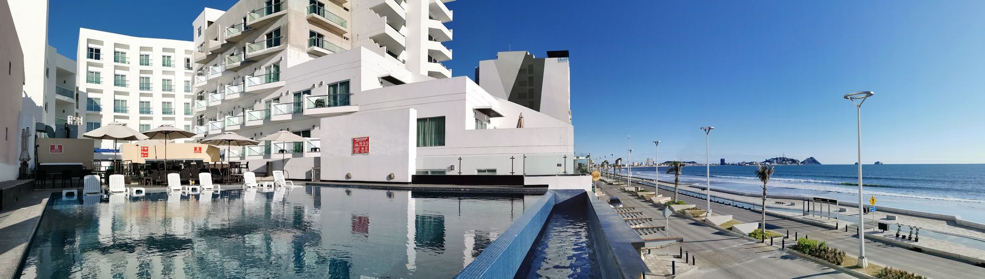 There is a large swimming pool in front of a hotel.