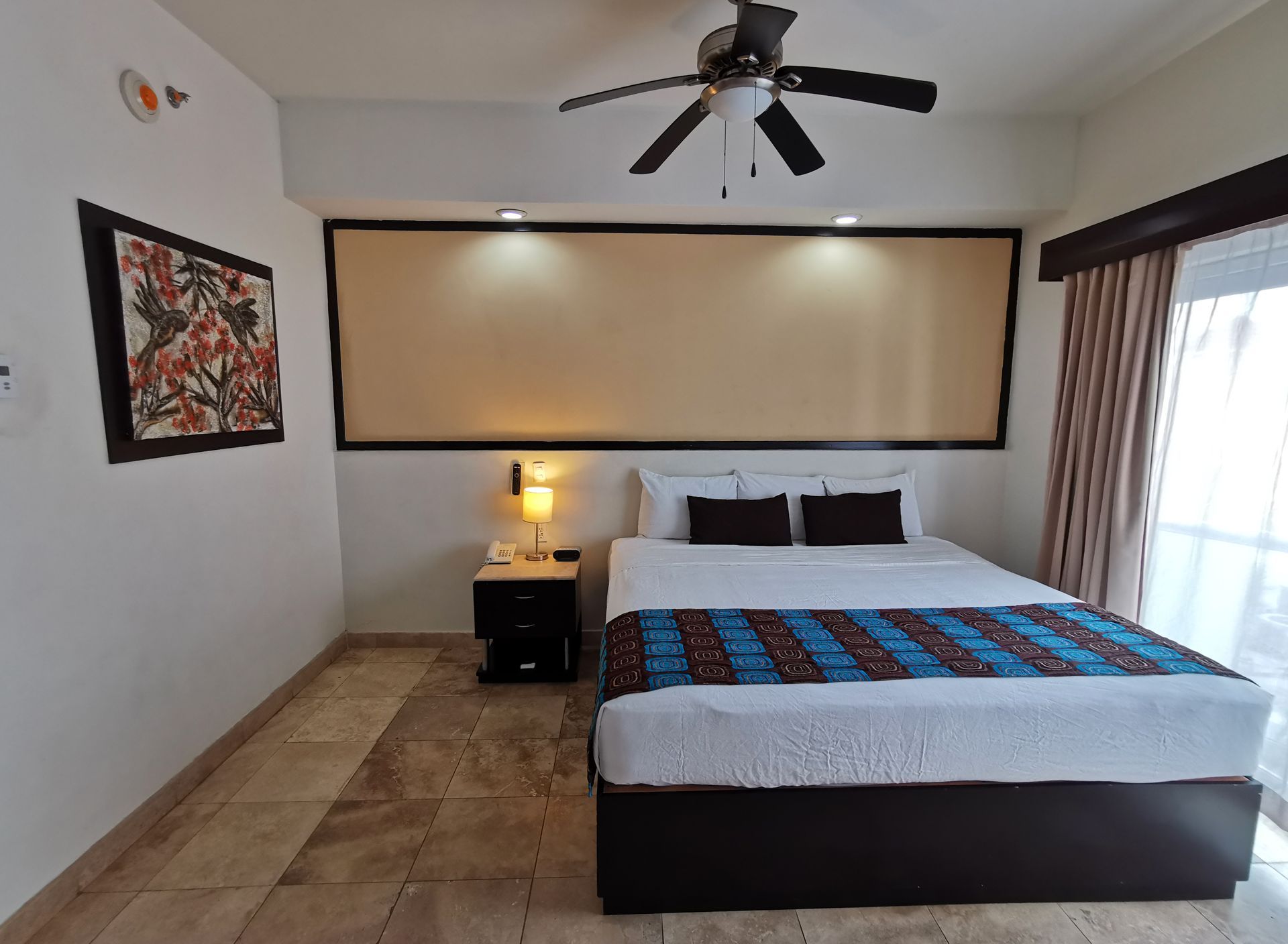 A hotel room with a large bed and a ceiling fan