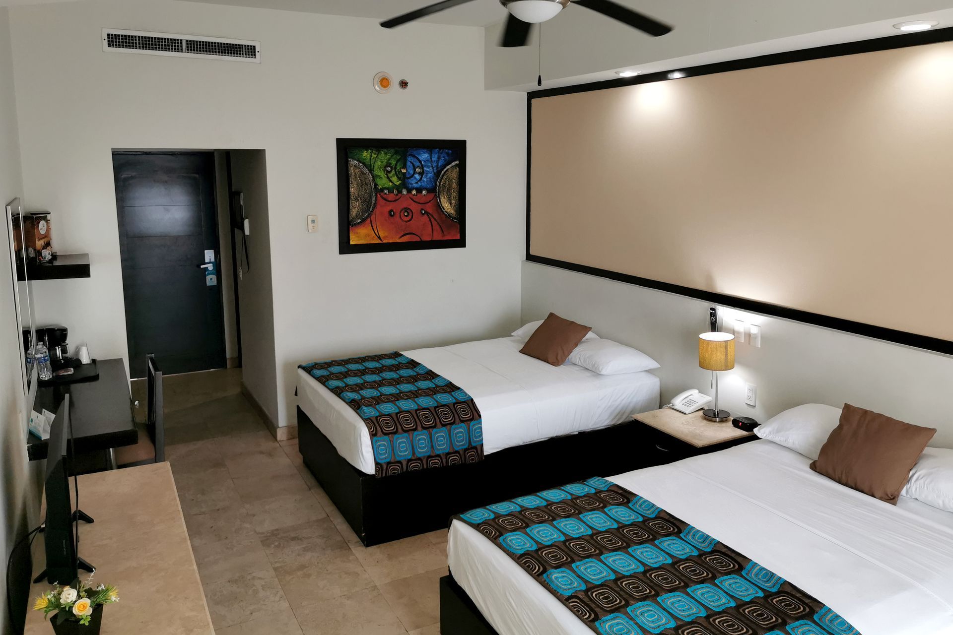A hotel room with two beds and a painting on the wall