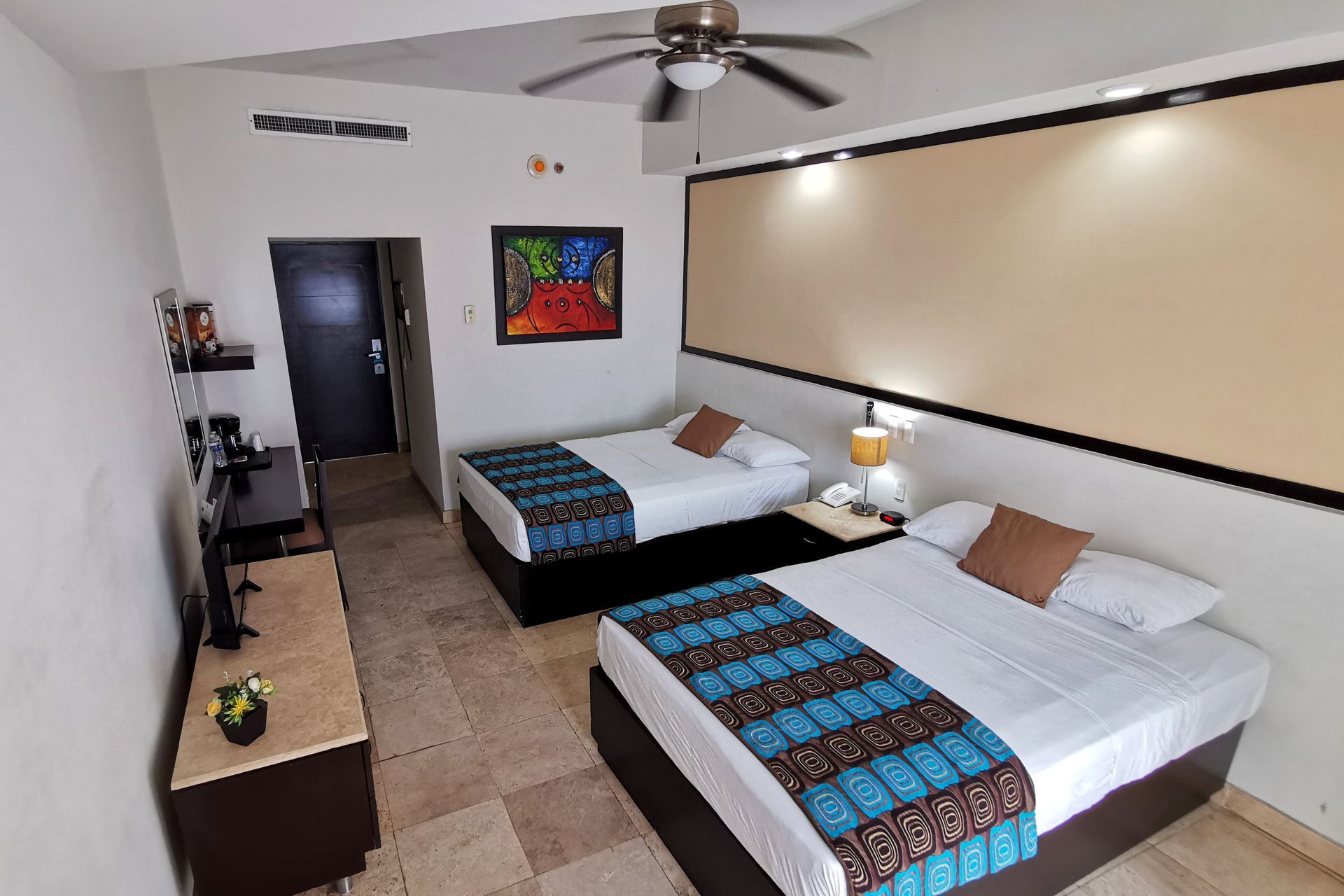 A hotel room with two beds and a ceiling fan