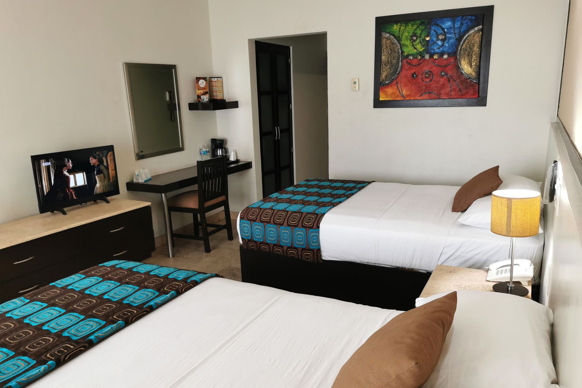 A hotel room with two beds , a desk and a television.