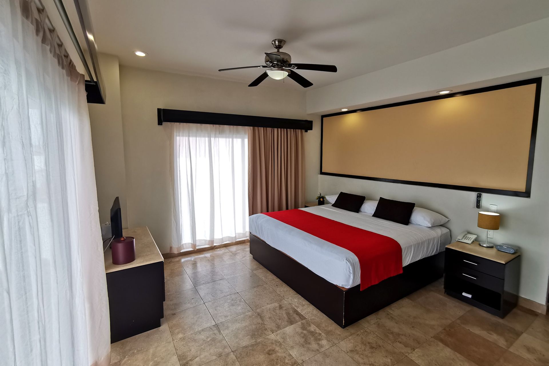 A hotel room with a king size bed and a ceiling fan