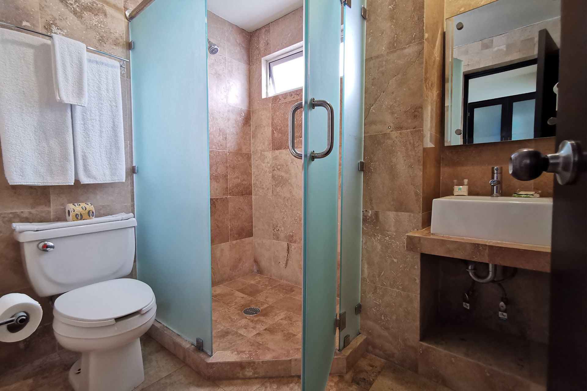 A bathroom with a toilet , sink , shower and mirror.