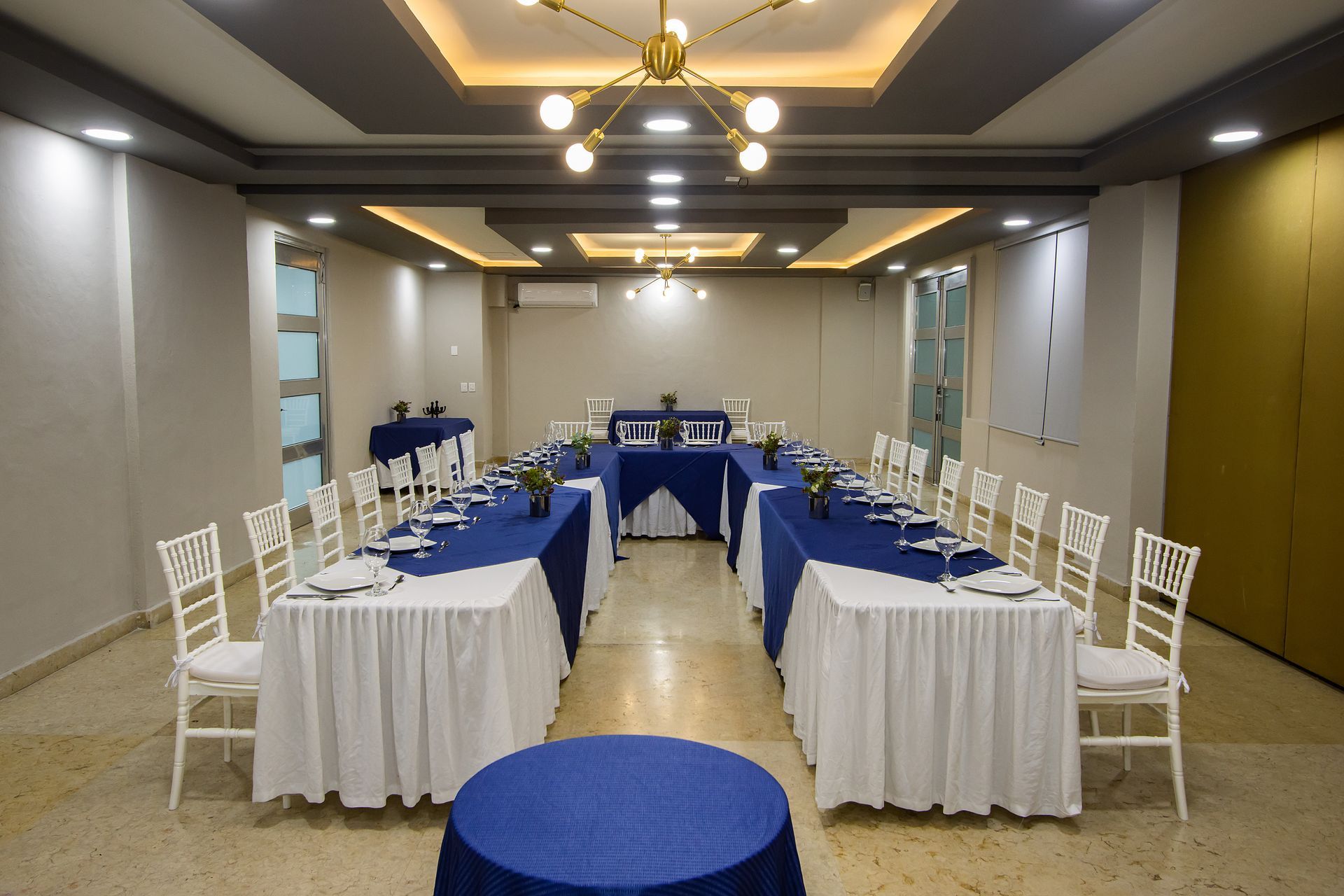 Una sala grande con mesas y sillas preparadas para una reunión.