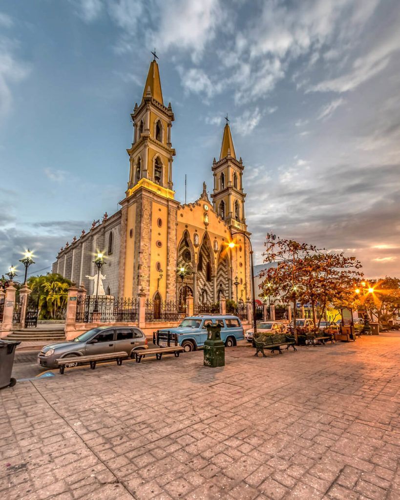 A large church with a lot of cars parked in front of it.