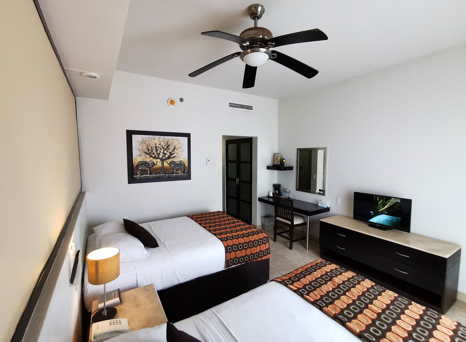 A hotel room with two beds and a ceiling fan