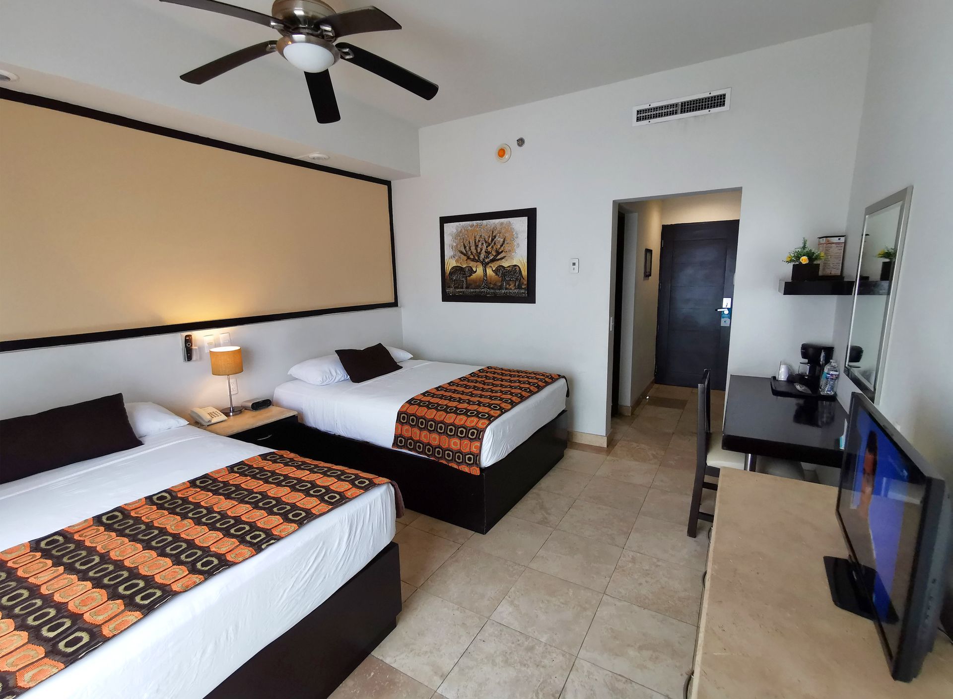 A hotel room with two beds and a flat screen tv