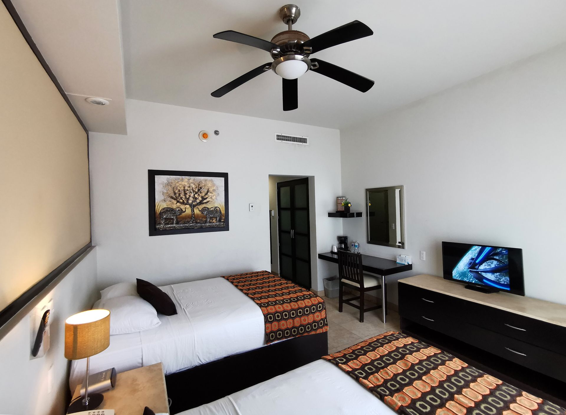 A hotel room with two beds and a ceiling fan