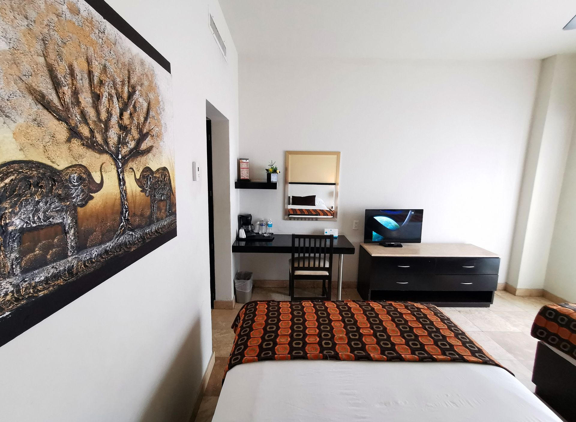 A bedroom with a painting of elephants on the wall