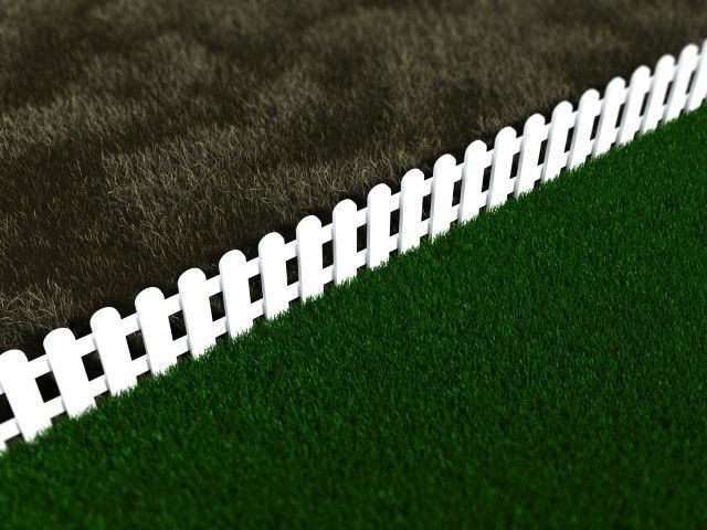 White picket fence bordering a green lawn at a diagonal angle