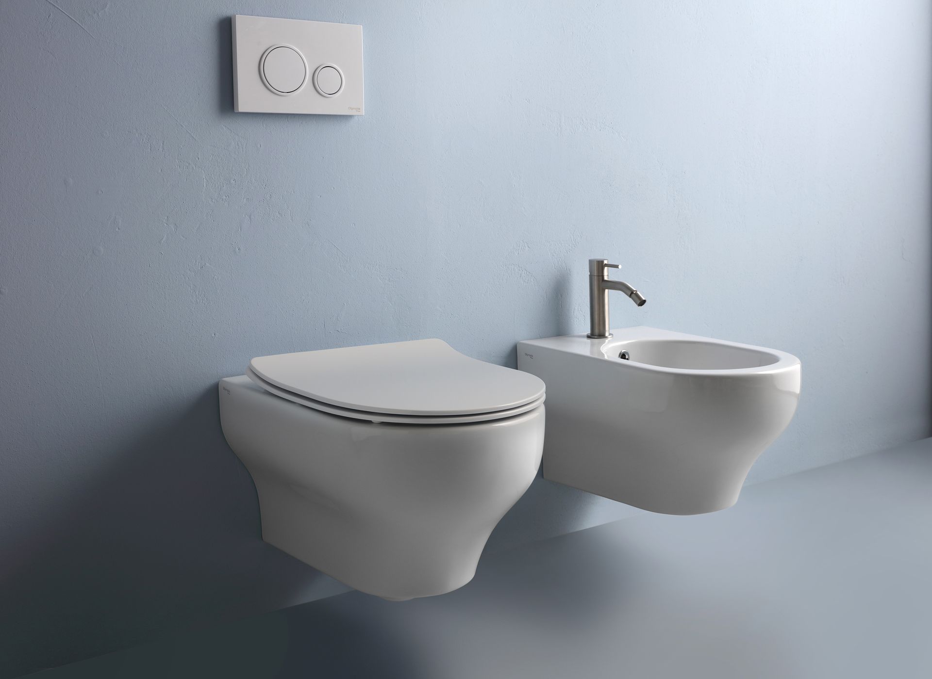 WC e bidet bianchi sospesi in un bagno con doppia piastra di scarico.