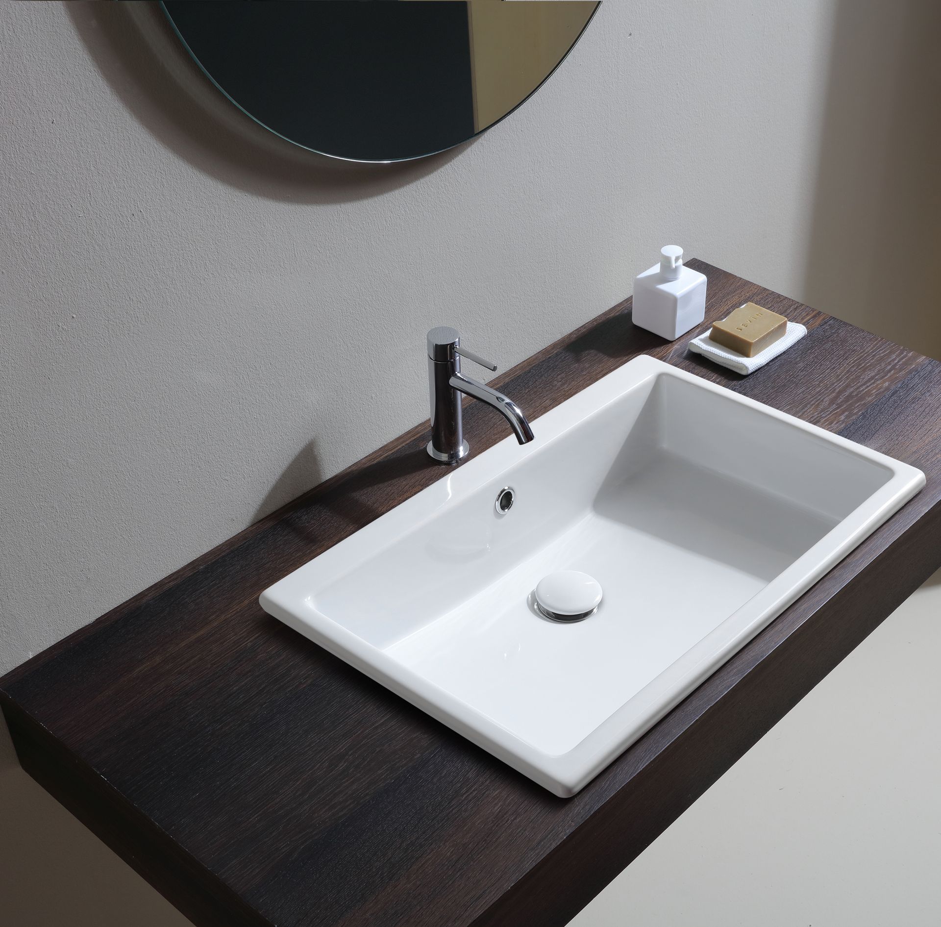 Lavandino rettangolare bianco con rubinetto cromato su piano in legno scuro.