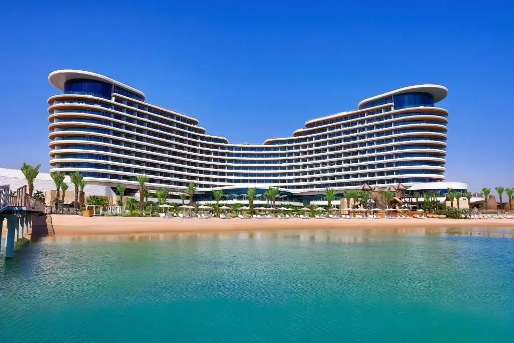Moderno hotel fronte mare con cielo azzurro e acqua turchese.