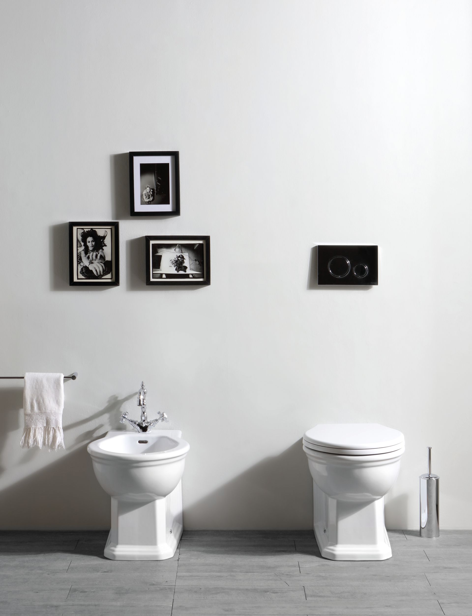 Bagno con bidet e WC, pareti bianche e quadri incorniciati.