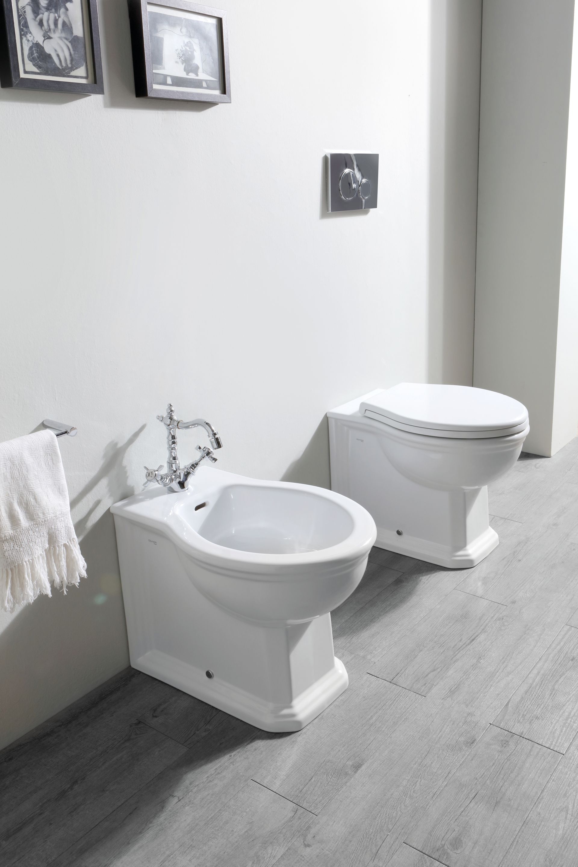 Bidet e WC bianchi in un bagno moderno con pavimento grigio chiaro e pareti bianche.