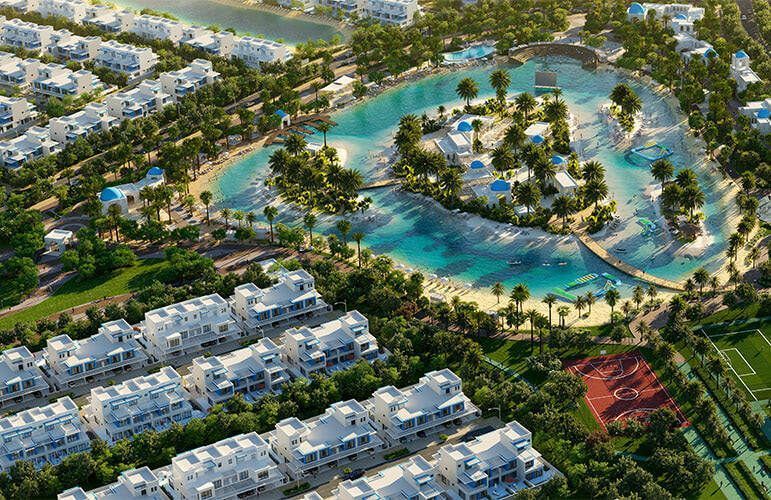 Vista aerea di un resort con edifici bianchi, una grande laguna blu e vegetazione.