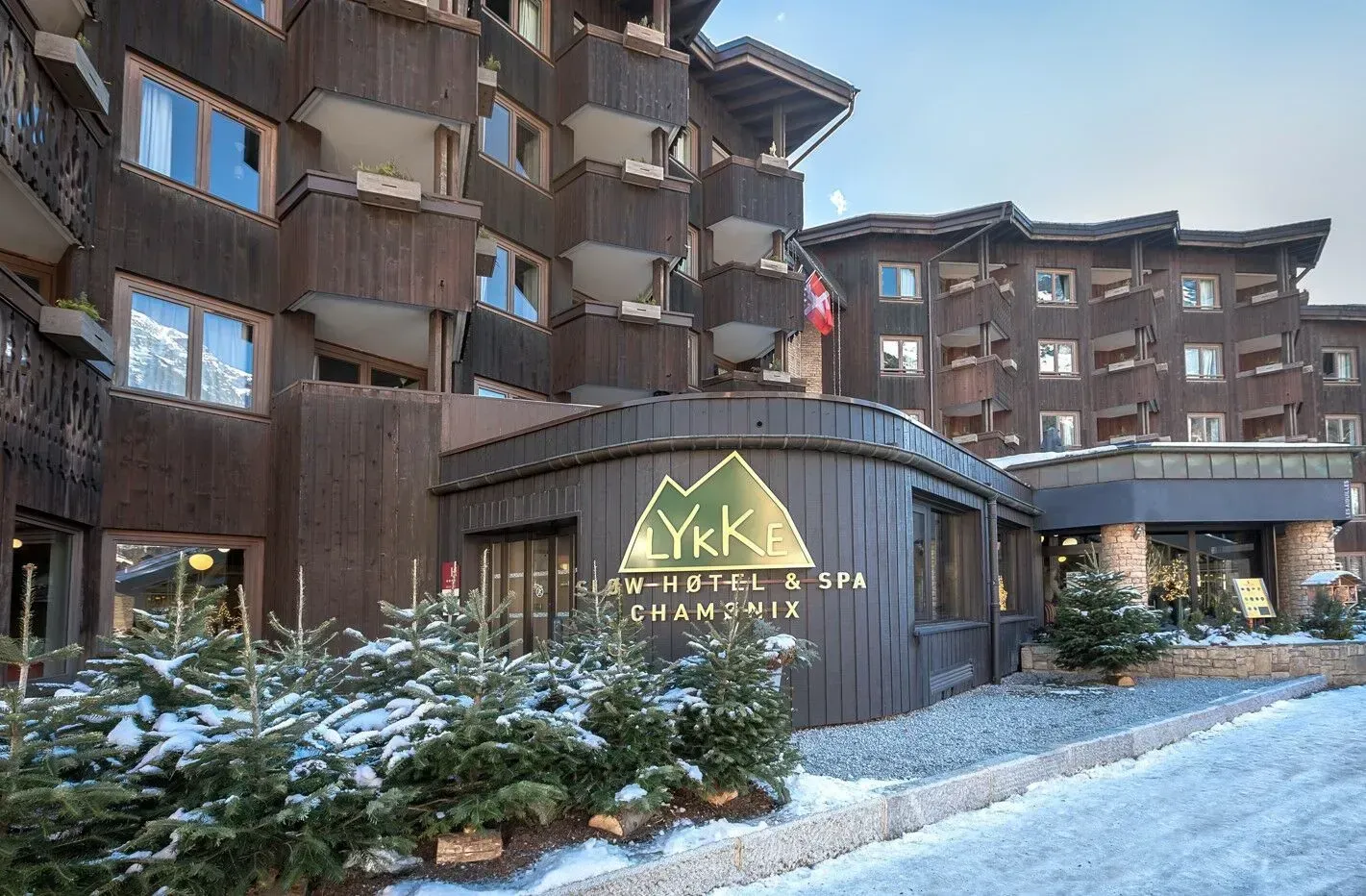 L'edificio del Brown Lykke Hotel & Spa nella neve. Alberi e una bandiera svizzera.