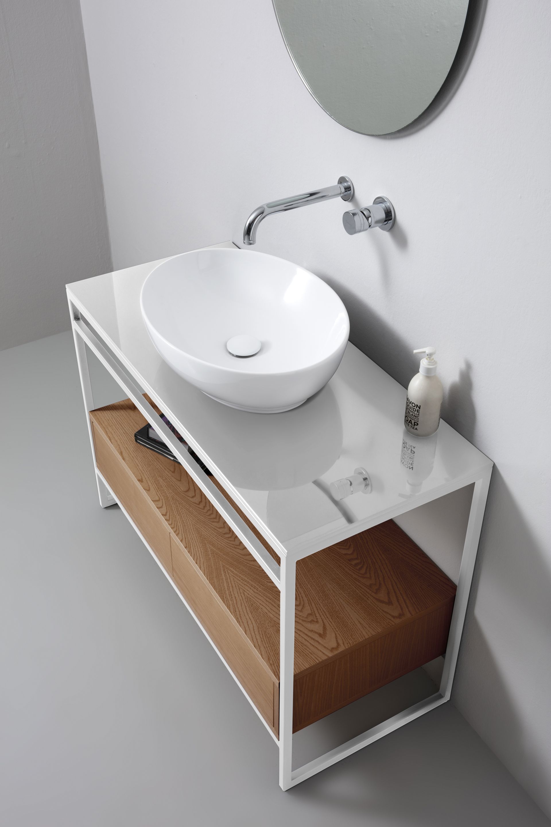 Lavandino ovale bianco su mobile con struttura in metallo bianco e cassetto in legno in un bagno moderno.