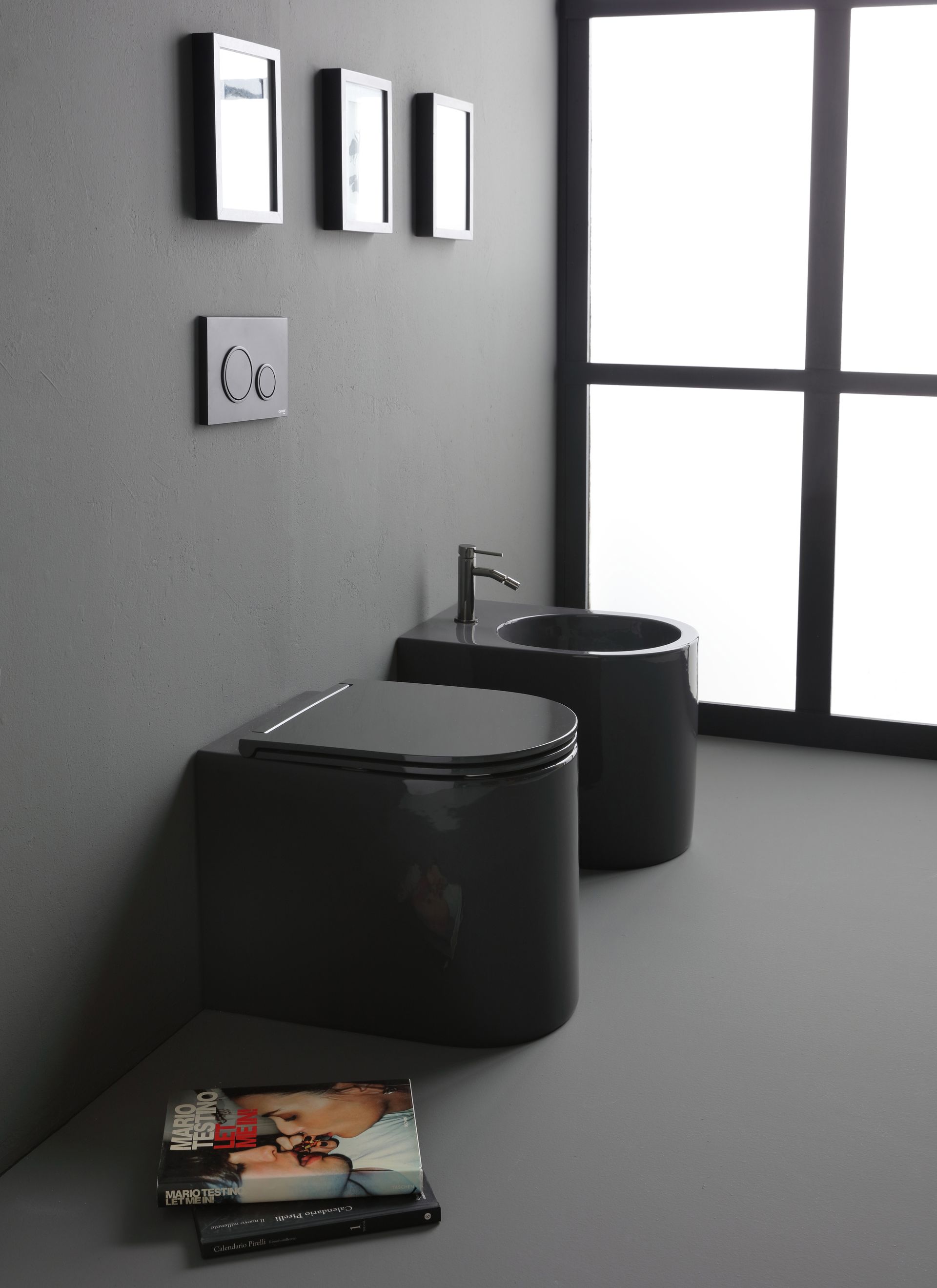 WC e bidet grigio scuro in un bagno moderno con una grande finestra e quadri incorniciati.