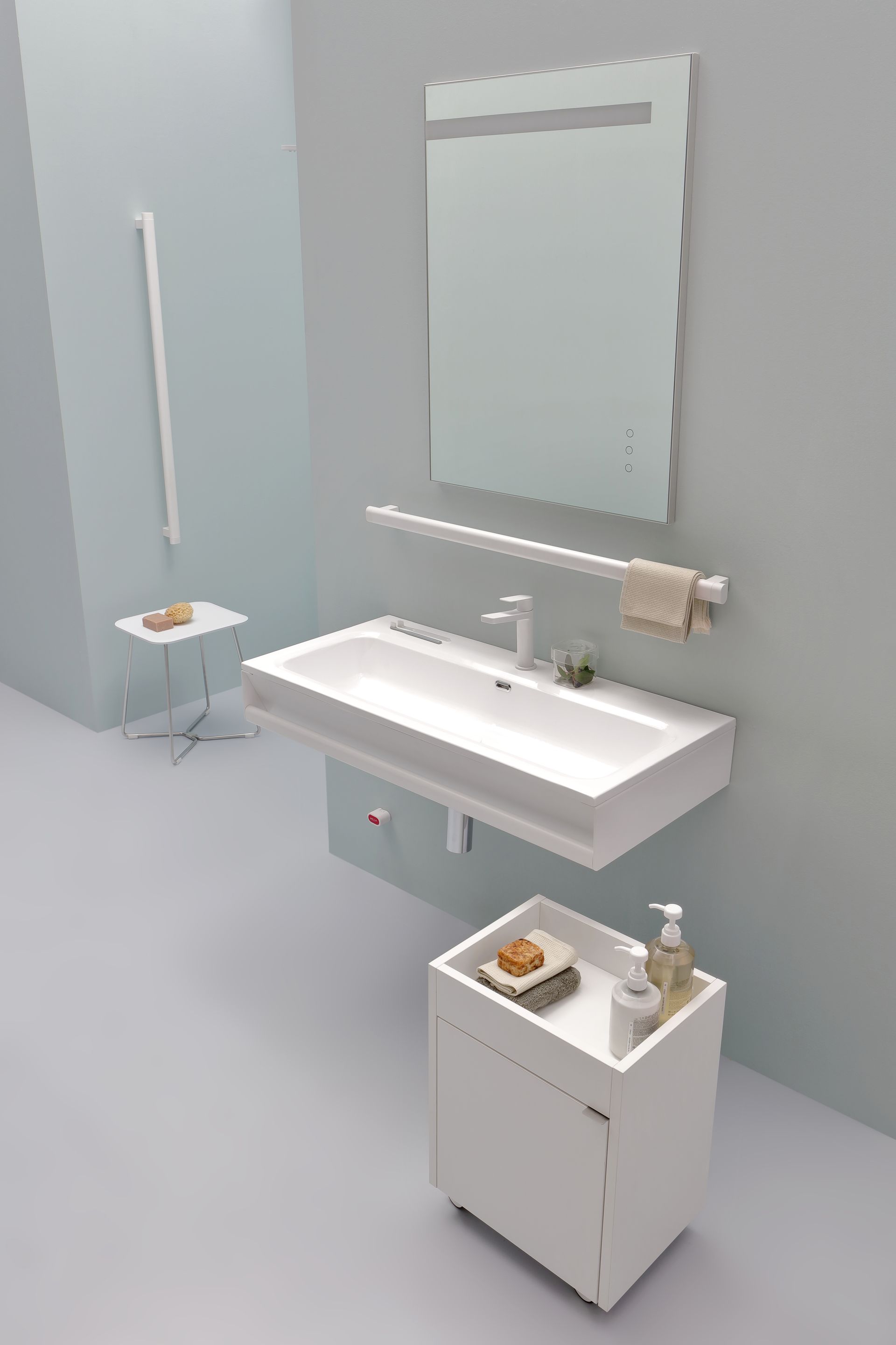 Moderno bagno bianco con lavandino sospeso, specchio e mobiletto su una parete azzurra.