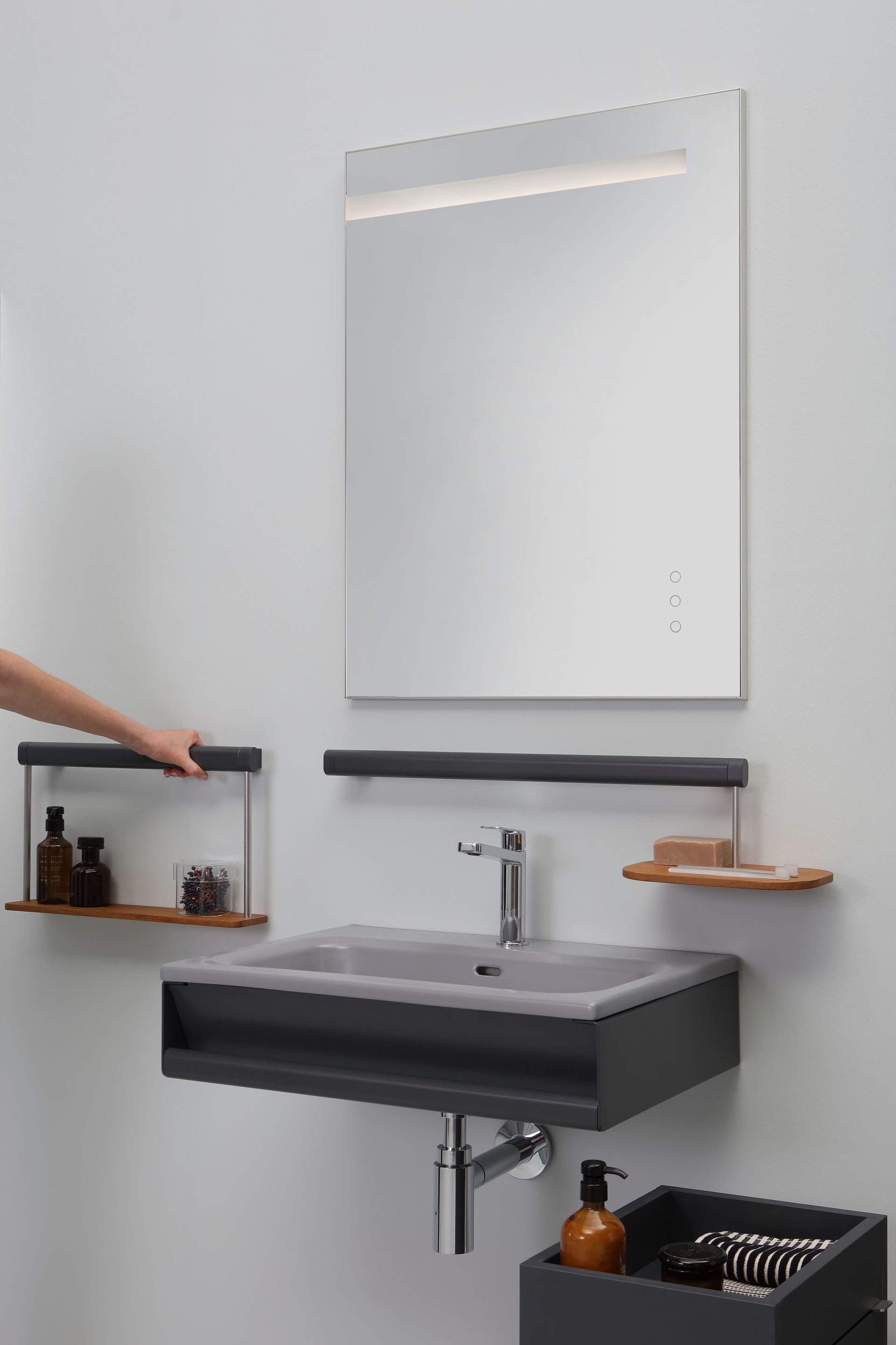 Mensola modulare a muro accanto a un moderno mobile da bagno con specchio, lavabo grigio e dettagli in legno.