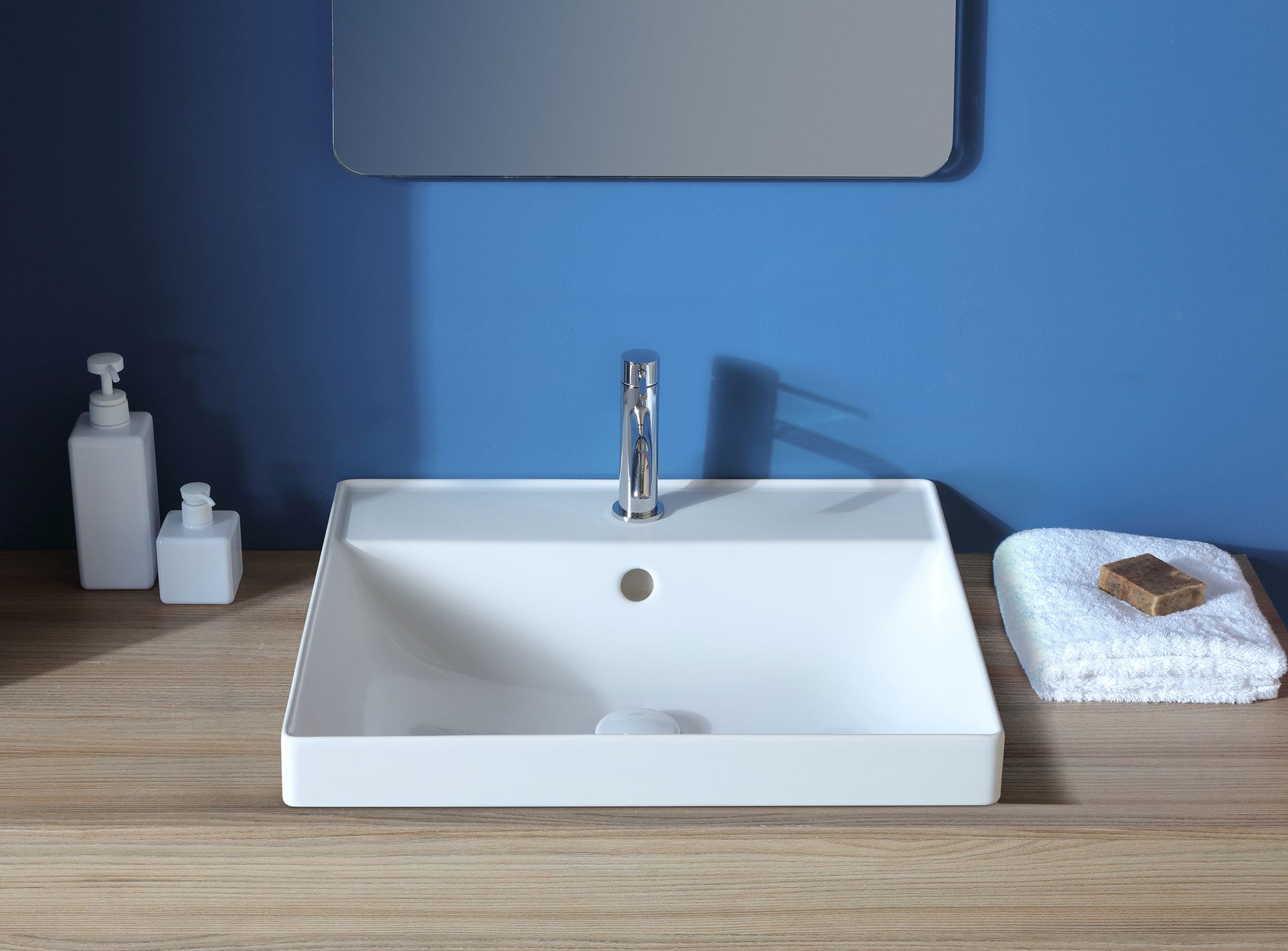 Lavandino rettangolare bianco con rubinetto cromato su superficie in legno.