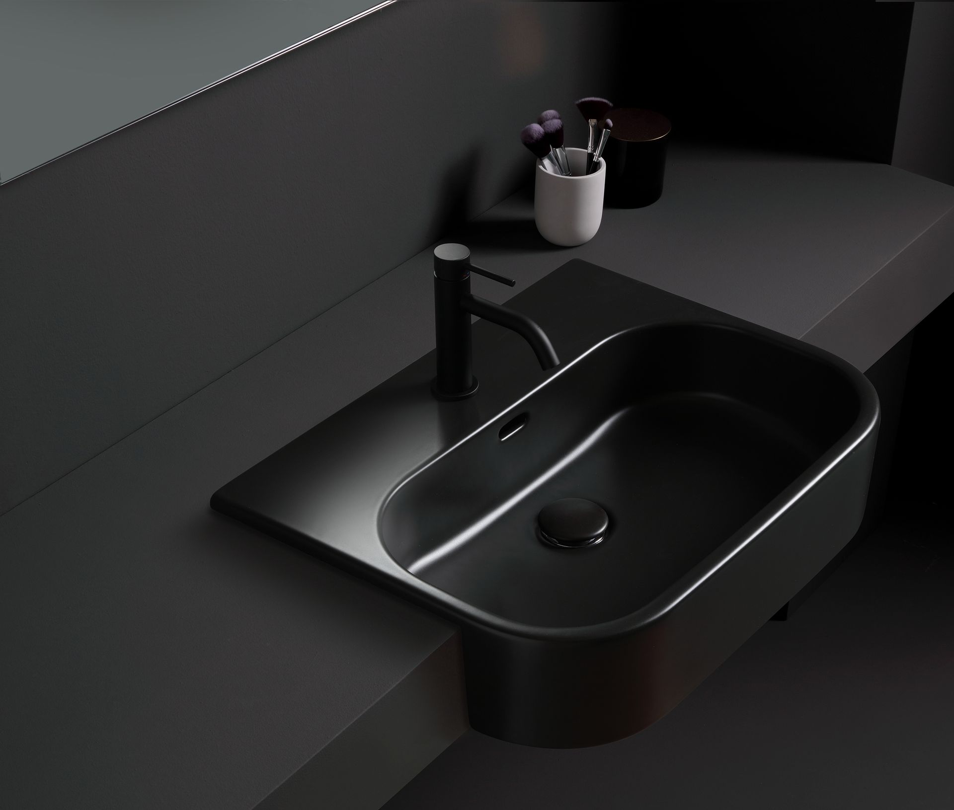 Lavandino nero con rubinetto nero, dispenser di sapone e articoli da toeletta.