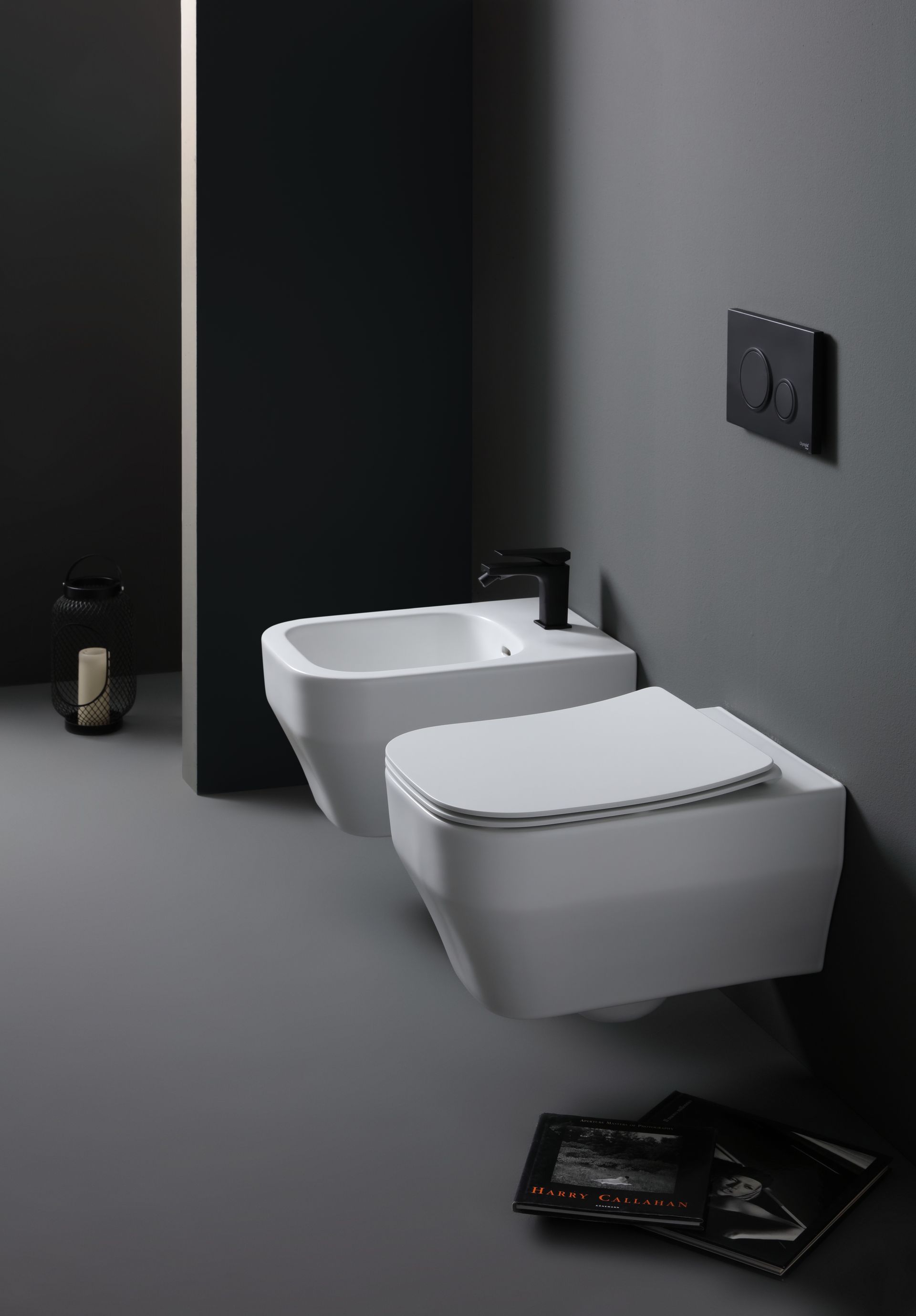 WC e bidet bianchi sospesi in un bagno moderno con pareti grigio scuro.
