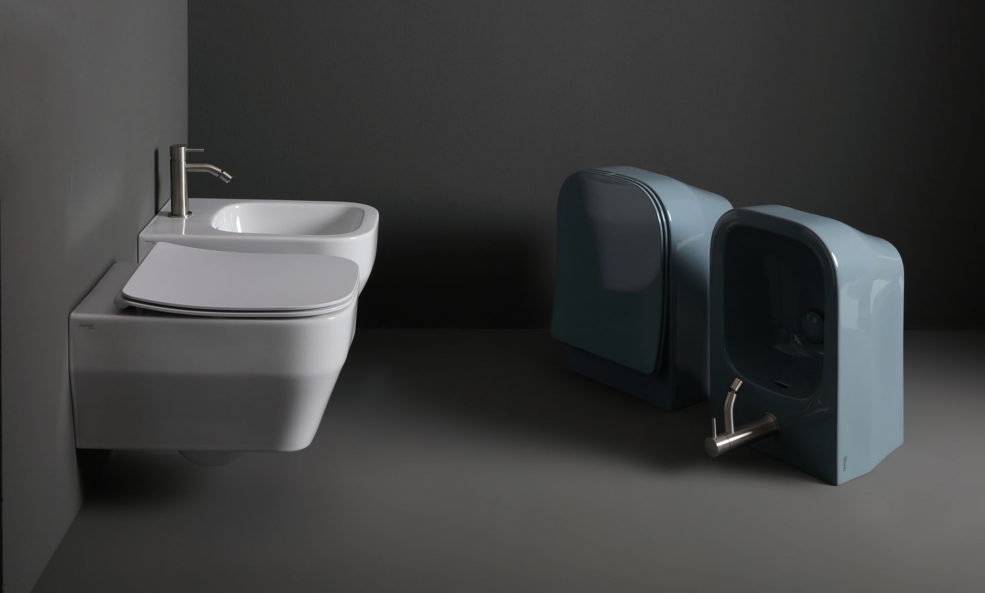 Moderno water e lavabo bianchi sospesi, bidet azzurro chiaro su pareti e pavimento grigi.