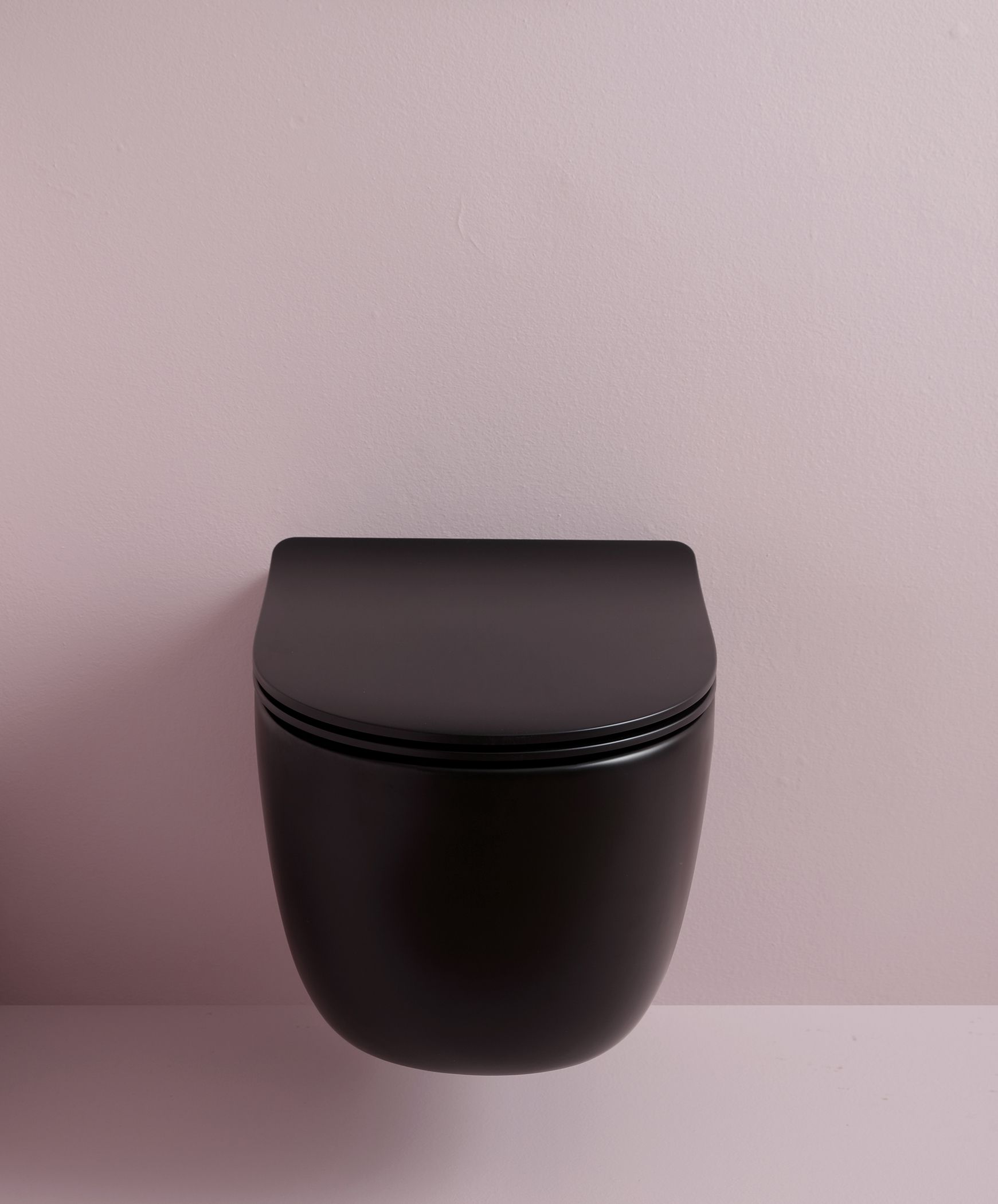 WC nero sospeso su una parete rosa pallido.