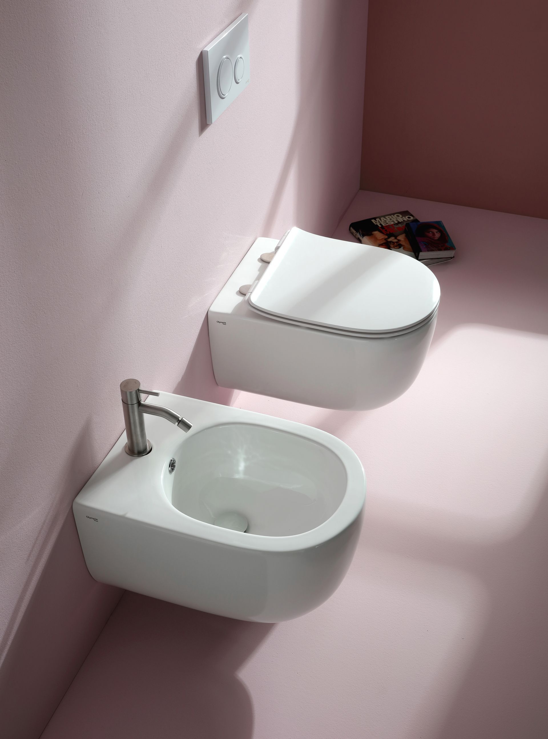 WC e bidet bianchi sospesi in un bagno con pareti rosa e rubinetto argentato.