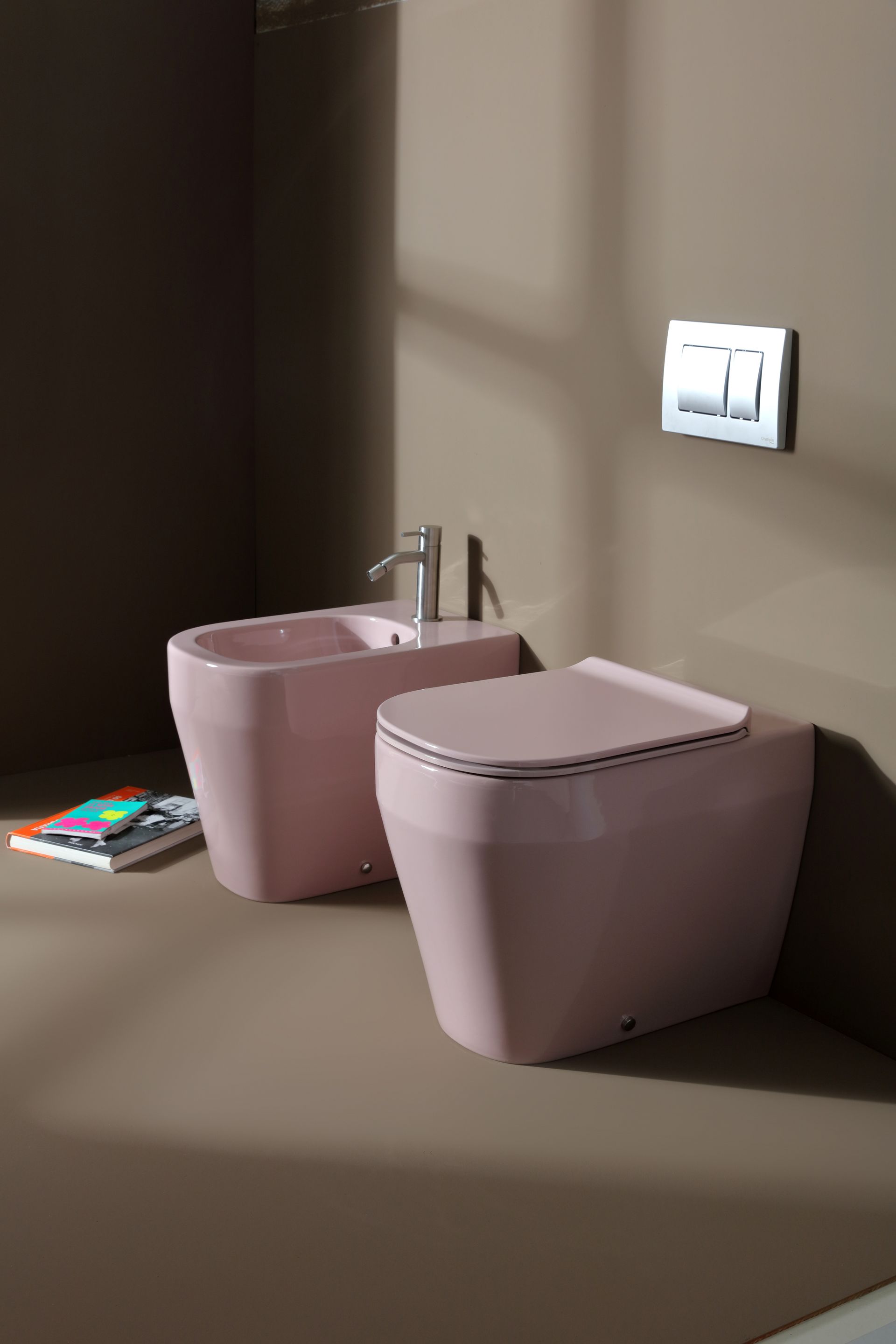 WC e bidet rosa in un bagno moderno, contro una parete marrone.