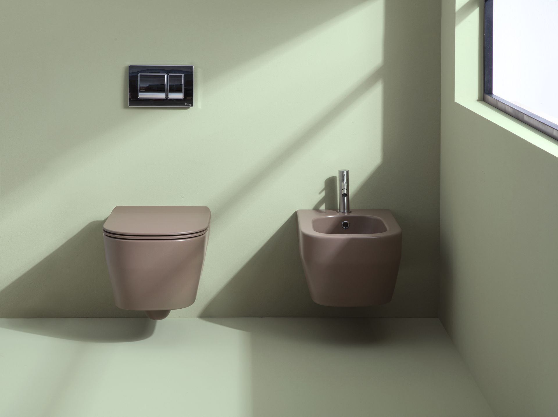 Bagno moderno con WC e bidet sospesi, color beige, con pannello a filo. Luce naturale proveniente da una finestra.