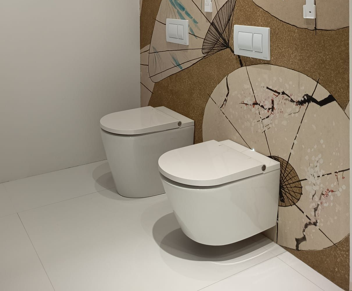 Due WC sospesi a parete in un moderno bagno piastrellato, uno bianco e uno grigio.