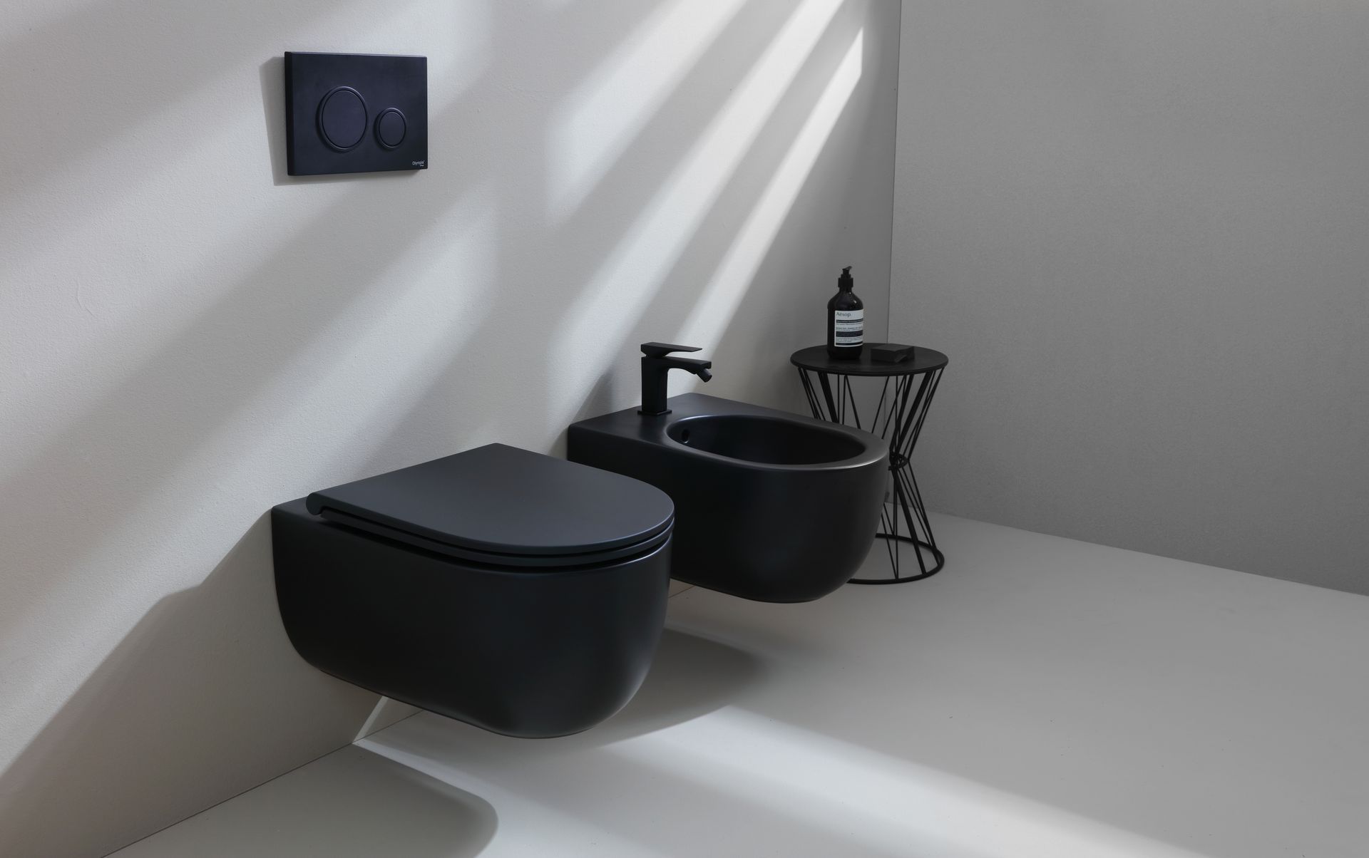 WC e bidet neri in un bagno moderno, con sanitari neri e un piccolo tavolino laterale.
